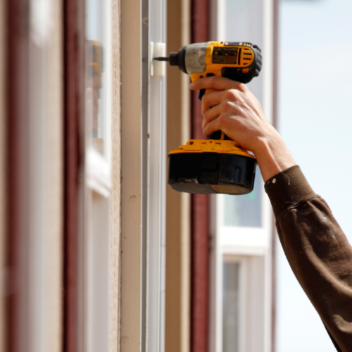 A yellow power drill being held and used 