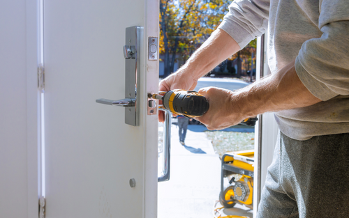 A close up of a power drill installing a door lock