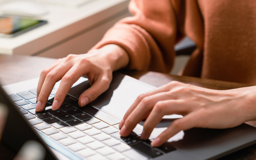 Hands typing on a laptop